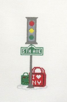 the cross stitch pattern shows a traffic light and street sign with bags on it, in front of a white background