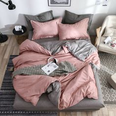 an unmade bed with pink and grey sheets