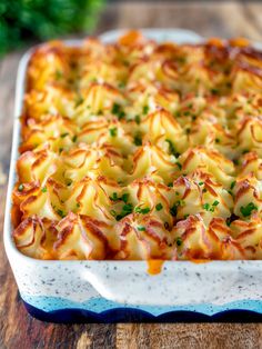 a casserole dish with cheese and parsley in it on a wooden table