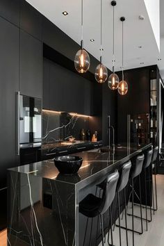 a modern kitchen with marble counter tops and black cabinets, lights hanging from the ceiling