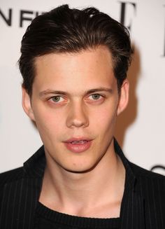 a close up of a person wearing a black shirt and looking at the camera with a serious look on his face