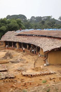 a group of people standing in front of a building with roof tiles on top of it