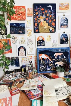 an artist's desk with art work on the wall