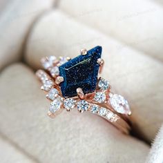 a blue diamond ring sitting on top of a white cushion