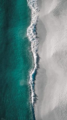 an aerial view of the ocean and beach with waves coming in from the sand to the water