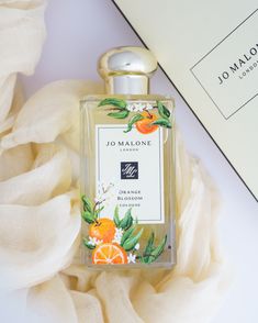 a bottle of jo malone orange blossom cologne sitting on top of a white cloth next to a box