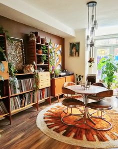 a living room filled with furniture and lots of plants on top of a wooden floor