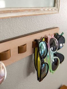 several pairs of sunglasses are hanging on the wall next to an eyeglass holder and mirror