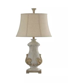 a white lamp with a beige shade on it's base and an ornate design