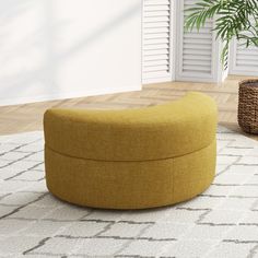 a large yellow ottoman sitting on top of a rug in a living room next to a potted plant