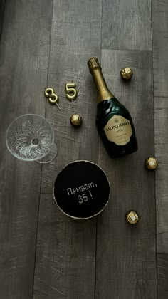 a bottle of champagne and some chocolates on a wooden table with the number 55