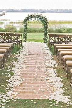 an outdoor ceremony setup with chairs and flowers on the aisle, along with petals scattered all over the ground