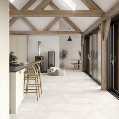 an open kitchen and living room with wood beams on the ceiling, white tile flooring