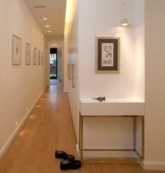 a pair of black shoes sitting on the floor in front of a white wall with framed pictures