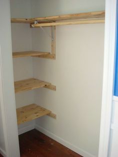 an empty closet with wooden shelves in it