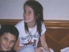 a young man sitting next to a woman on top of a bed