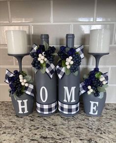 three wine bottles decorated with flowers and the word home are sitting on a kitchen counter