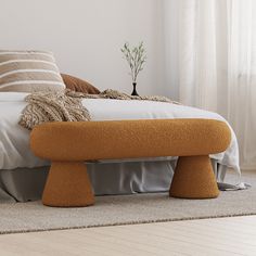 a bed with an orange foot stool next to it on top of a carpeted floor