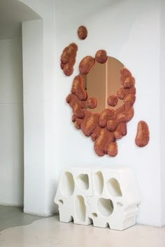 a mirror that is on the wall next to a white bench and some rocks in front of it