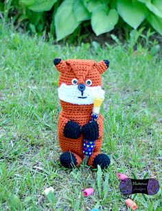 a crocheted fox holding an ice cream cone in its mouth sitting on the grass