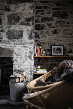 a living room with stone walls and a chair next to a firewood log holder