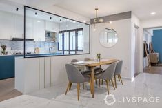 a dining room table and chairs in front of a kitchen with blue cabinets, marble flooring and white walls