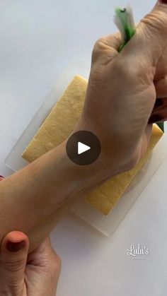 a person is using a sponge to clean their hand with a green and yellow cloth