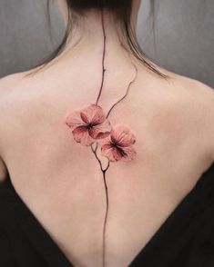 the back of a woman's neck with pink flowers on it