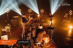 a group of people that are on stage with some lights in the dark behind them