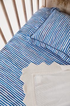 a baby crib with blue and white striped sheets on it's bedding