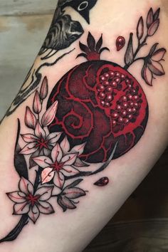 a woman's thigh with flowers and a pomegranate tattoo on it