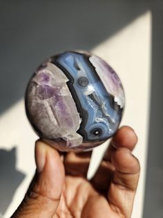 a person holding a marble ball in their left hand with the reflection of another object on it