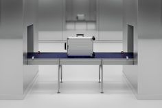 a suitcase sitting on top of a blue table in an empty room with metal partitions