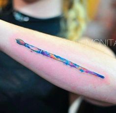 a watercolor painting style arrow tattoo on the arm