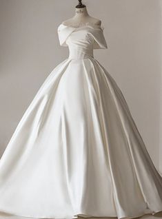 a white wedding dress on a mannequin with an off the shoulder neckline