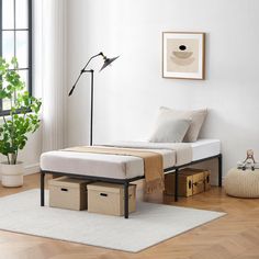 a bed sitting on top of a hard wood floor next to a lamp and window