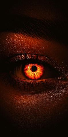 an orange eye in the dark with light coming from it's iris and eyeshade