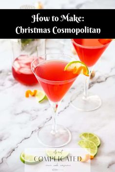 two glasses filled with christmas cosmopolian and garnished with limes