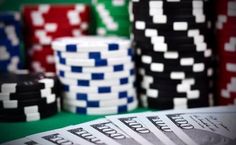 stacks of money and poker chips on a green table with red, white, and blue cards