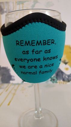 a blue wine glass with a black band around the rim that says, remember as far as everyone knows we are a nice normal family