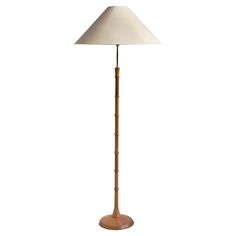 a wooden floor lamp with a white shade