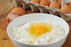 an egg is in a white bowl next to some eggs on the table with other ingredients