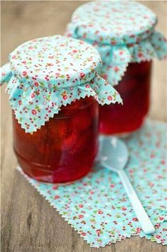 two jars filled with jam sitting on top of a table next to a spoon and napkin