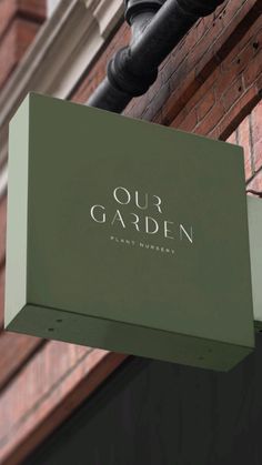 a sign hanging from the side of a brick building that says our garden plant nursery