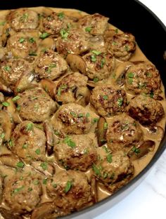 a pan filled with meatballs covered in gravy and garnished with parsley