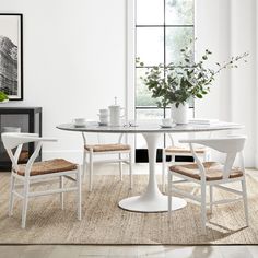 a white table and chairs in front of a window with potted plants on it