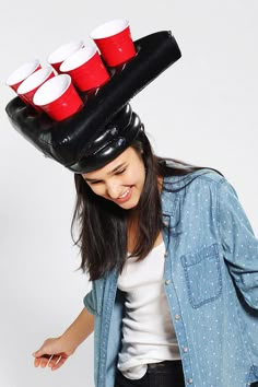 a woman wearing a hat with red cups on it's top and her hair blowing in the wind