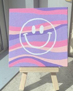 a small easel with a painted smiley face on it's front and side