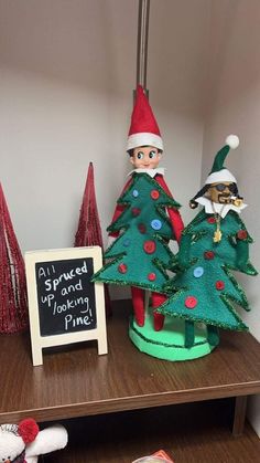 two christmas trees with elf hats on and a sign that says, all i spruced up looking pine