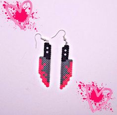 two pairs of pink and black earrings with hearts in the background on a white surface